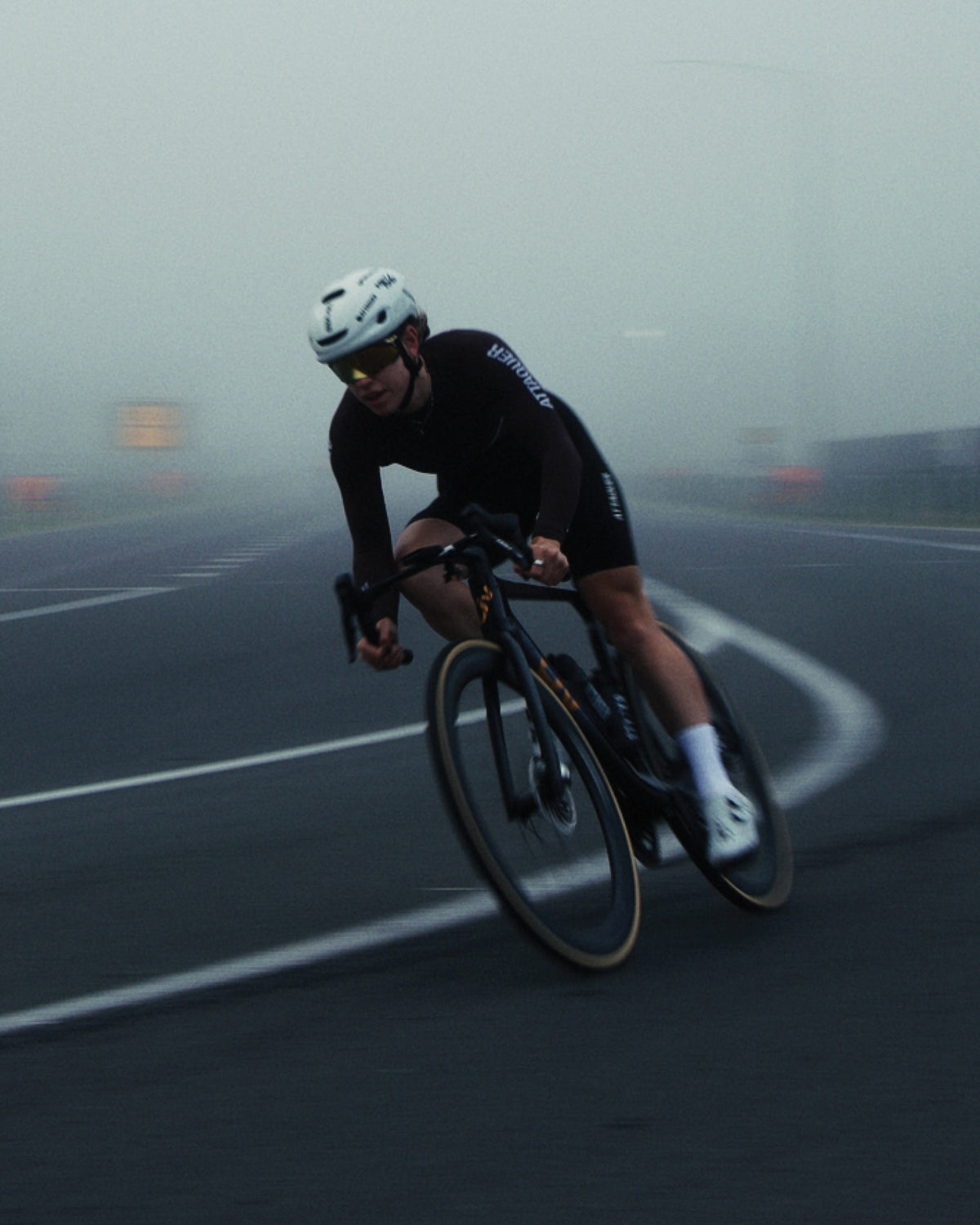 Attaquer rider in the black OrbKnit Race Jersey Long Sleeve cornering on a foggy road