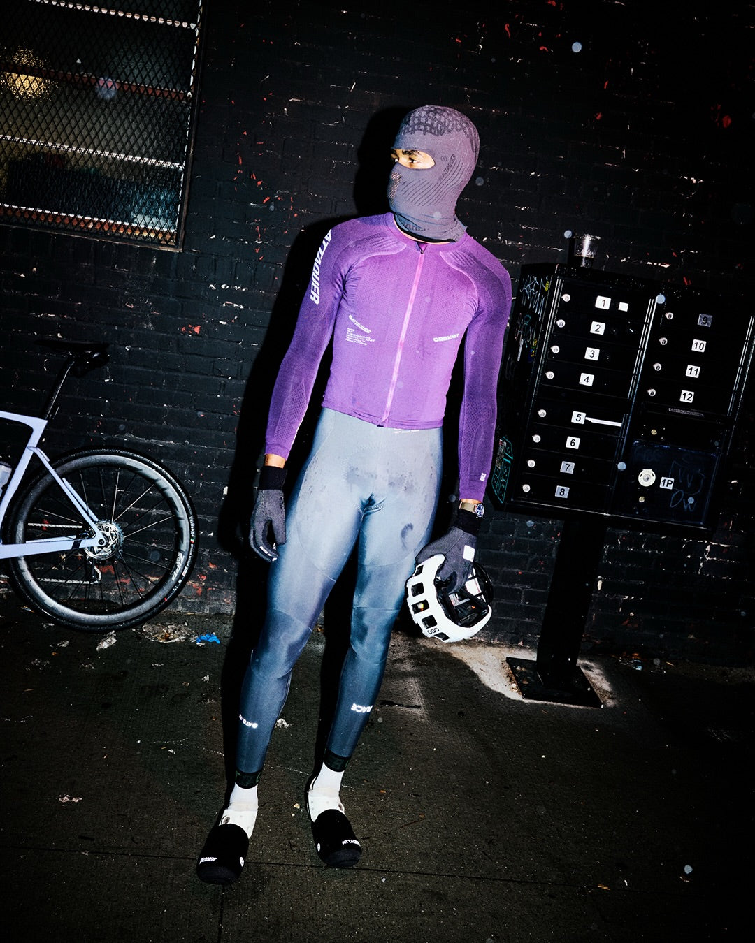 Attaquer rider in the purple OrbKnit Race Jersey Long Sleeve and Race Winter Bib Longs on a wet night street
